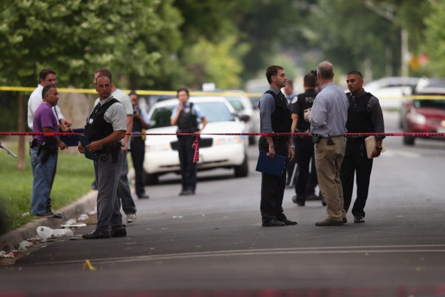 CHICAGO, IL - JULY 06: Police investigate a crime scene where seven people were shot on July 6, 2013 in Chicago, Illinois. Two days earlier and half of a block away Steve Mabins, 21, was shot and killed on his way to an Independence Day party. More than 60 people have been shot in Chicago since Wednesday, at least nine fatally. (Photo by Scott Olson/Getty Images)
